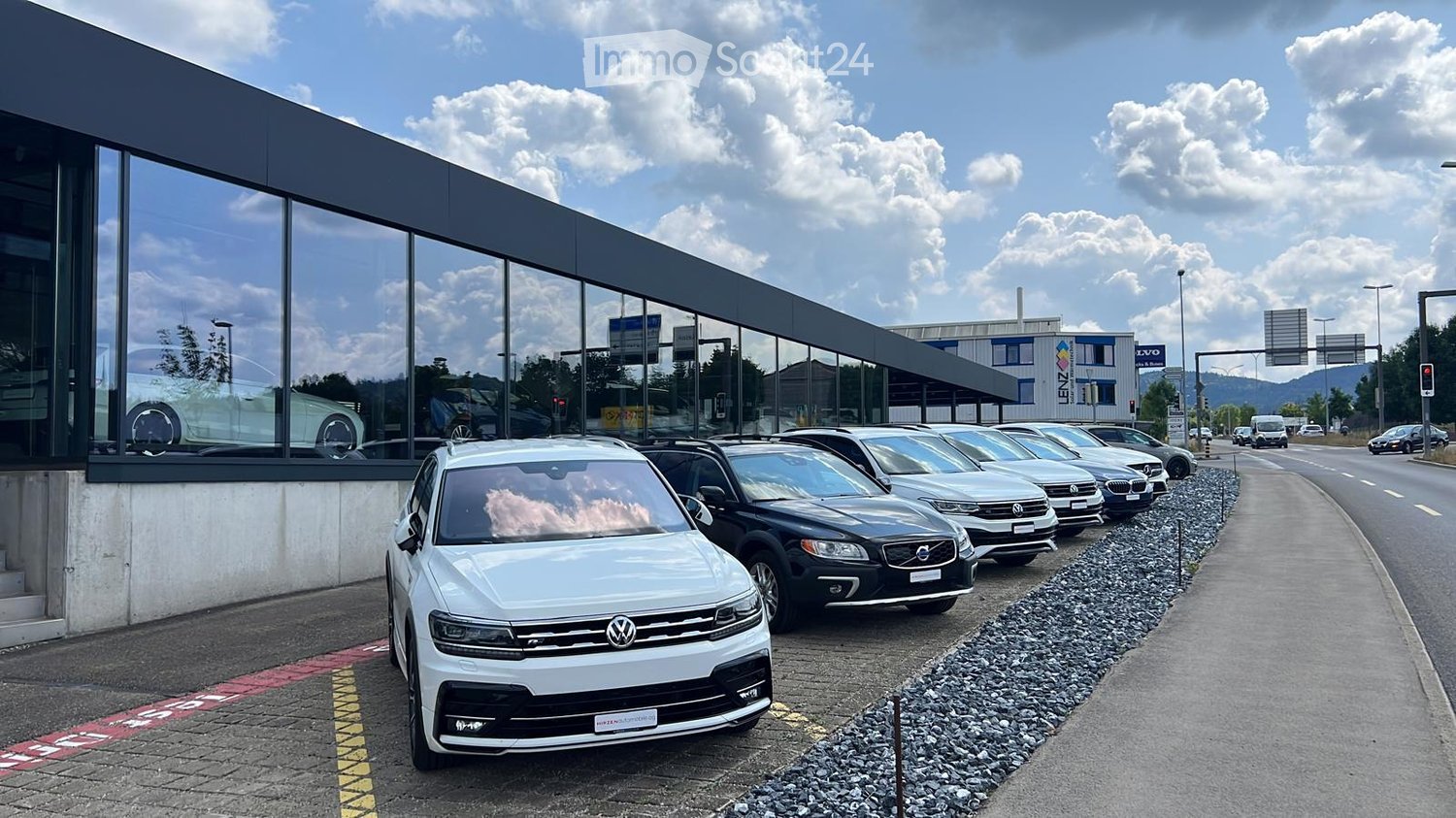 A row of parked cars in front of the showroom with glass walls.