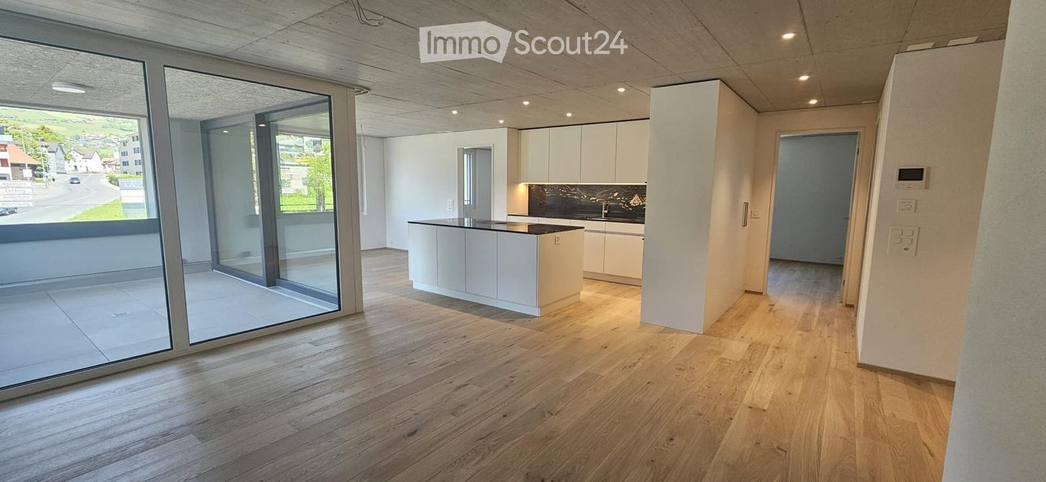 Modern, minimalist kitchen with white cabinets, a central island, and large glass sliding doors leading to a balcony.