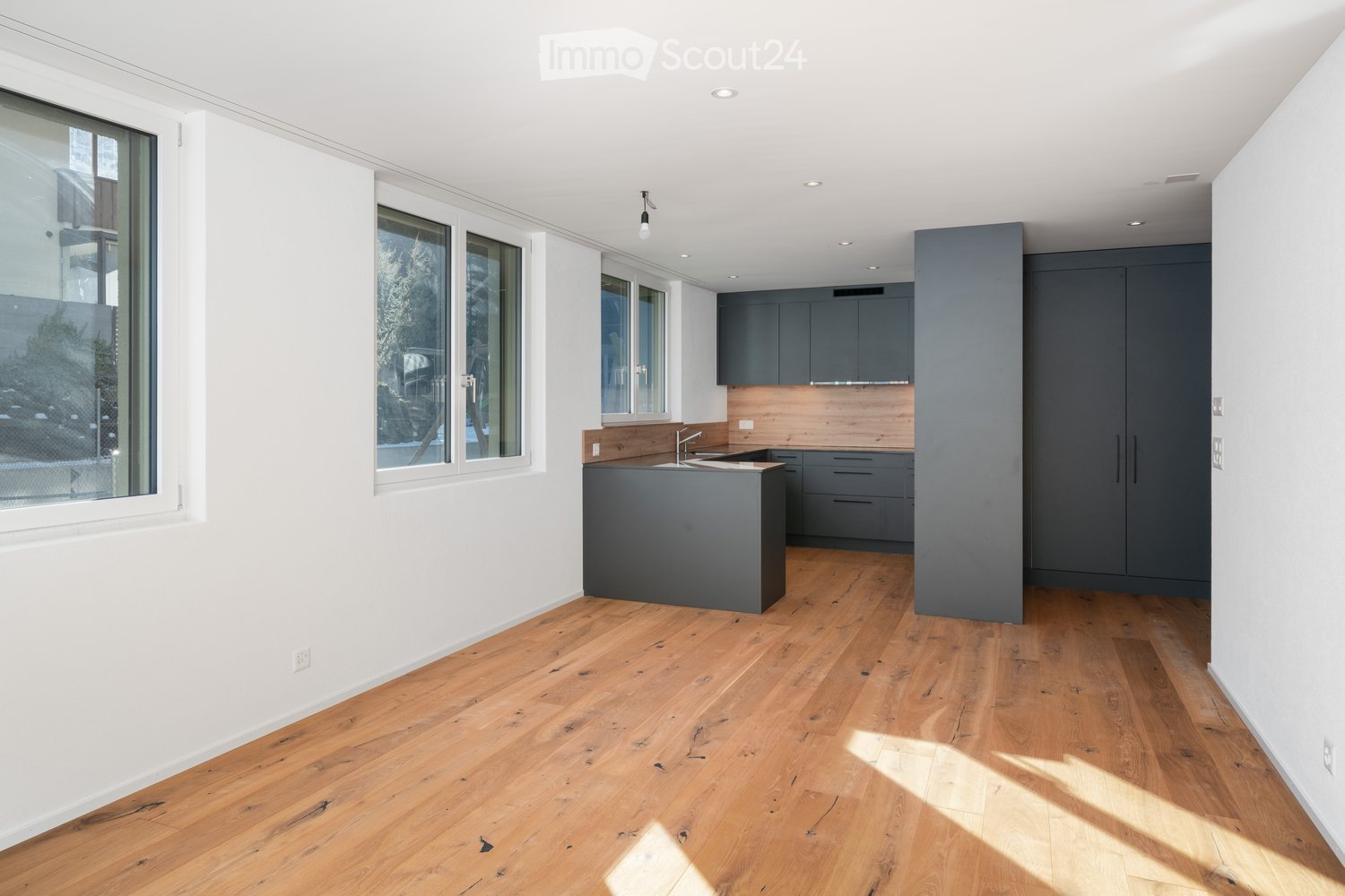 modern kitchen with island, wooden countertop, stainless steel sink, windows, hardwood floors, neutral color scheme