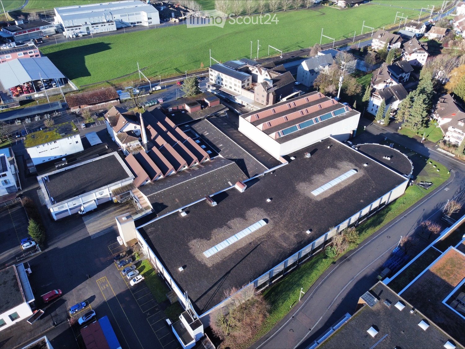 Industrial building with multiple levels, several car parking areas, and a wide area of grass