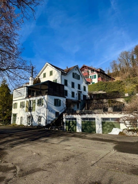 multi-story white house, large garage at the bottom, balconies and windows