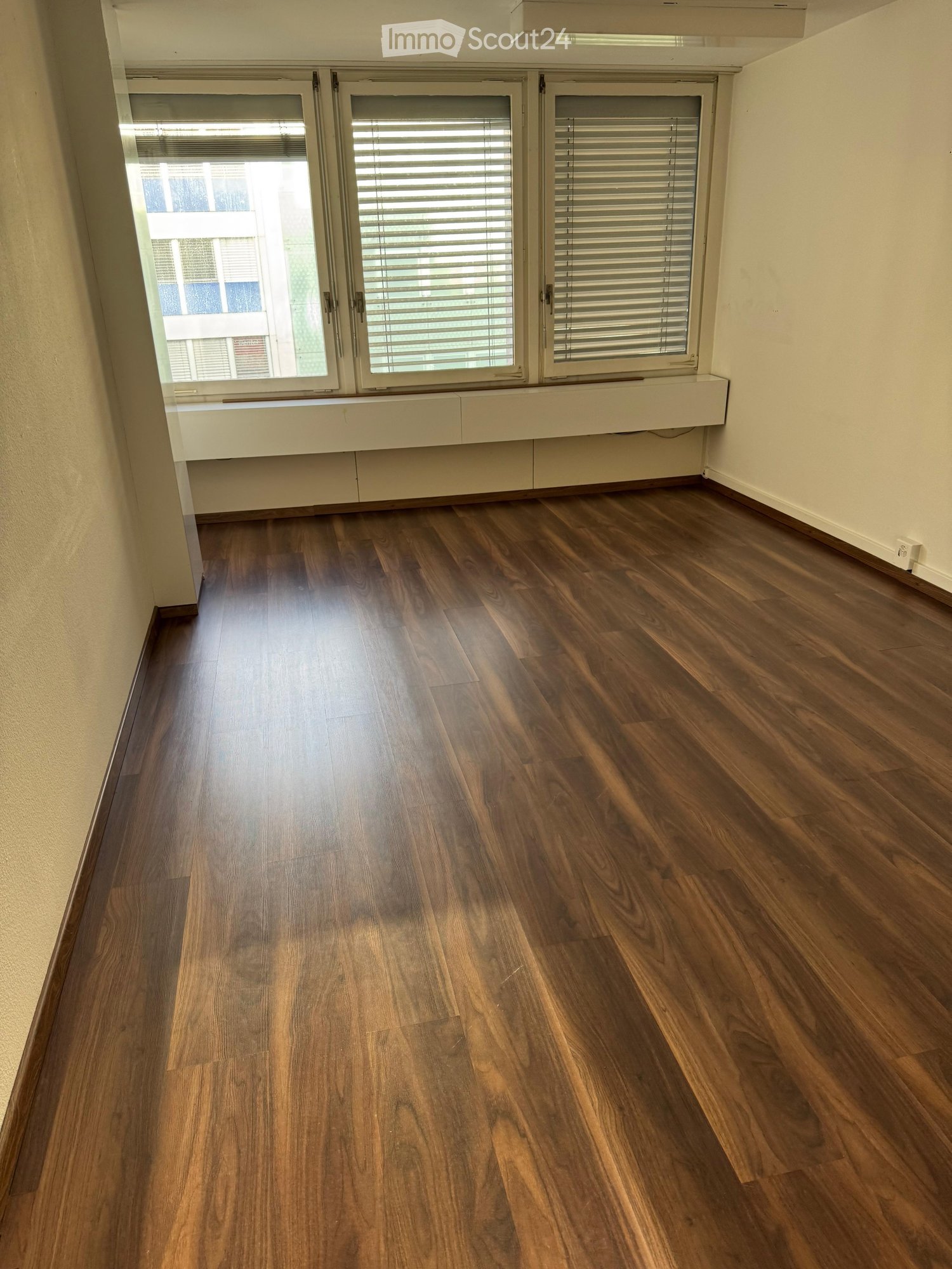 empty room with hardwood flooring, large windows, window seat, view of city