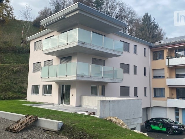 Modern apartment building, 3 floors, balcony, car parked in front, surrounding by trees