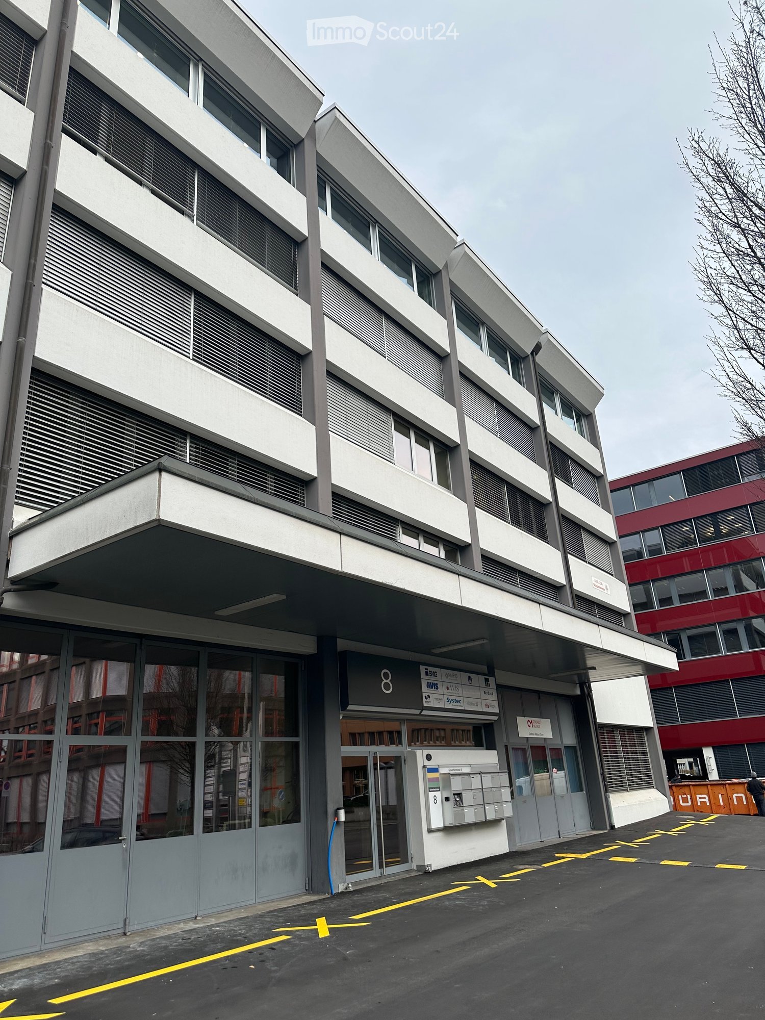 5 story building, glass windows, large entrance with glass doors, mail slots, number 8
