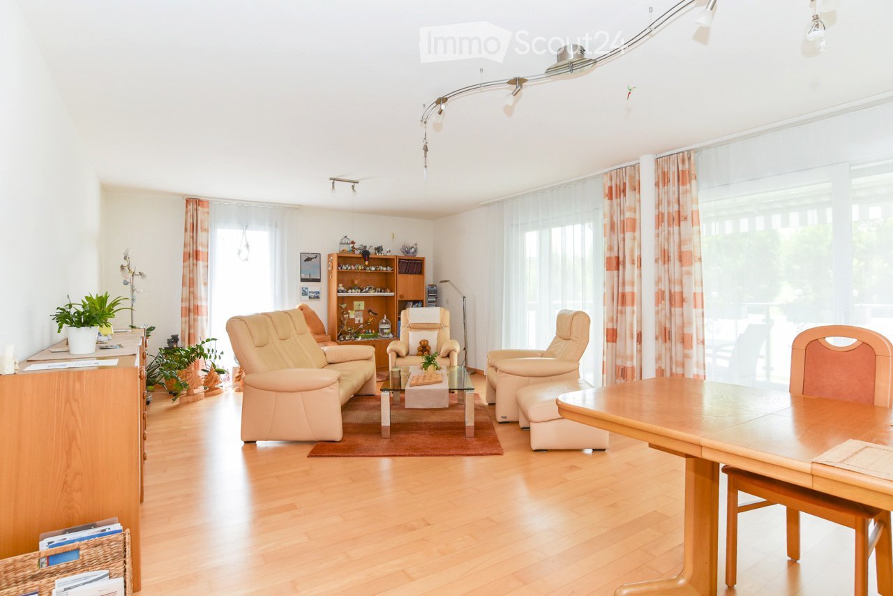 white walls, wooden floor, large windows, beige sofa, wooden coffee table, wooden dining table and chairs, plants, lamps, cabinet, curtains