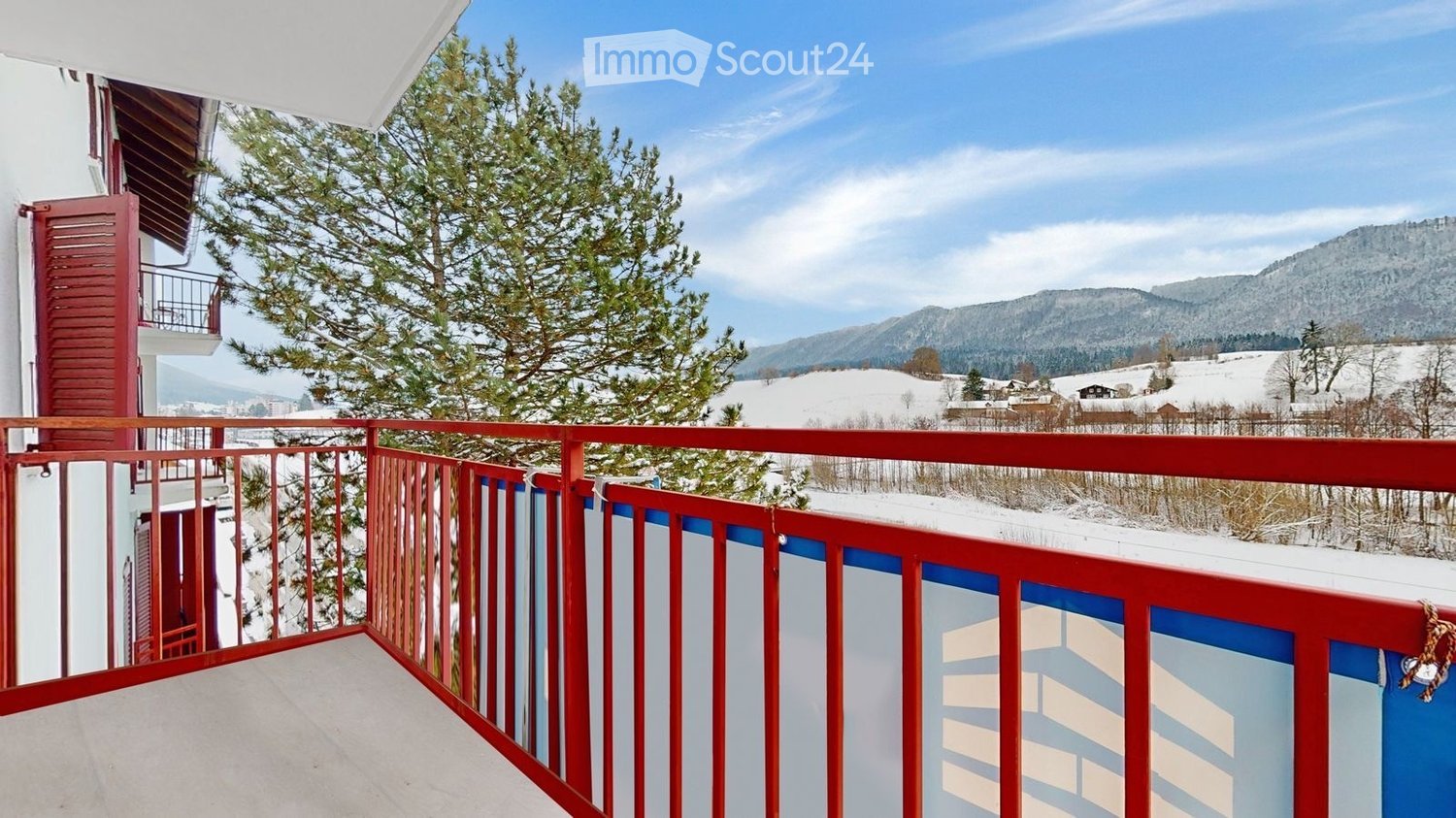 balcony with red railings, view of snowy mountains, pine tree in front