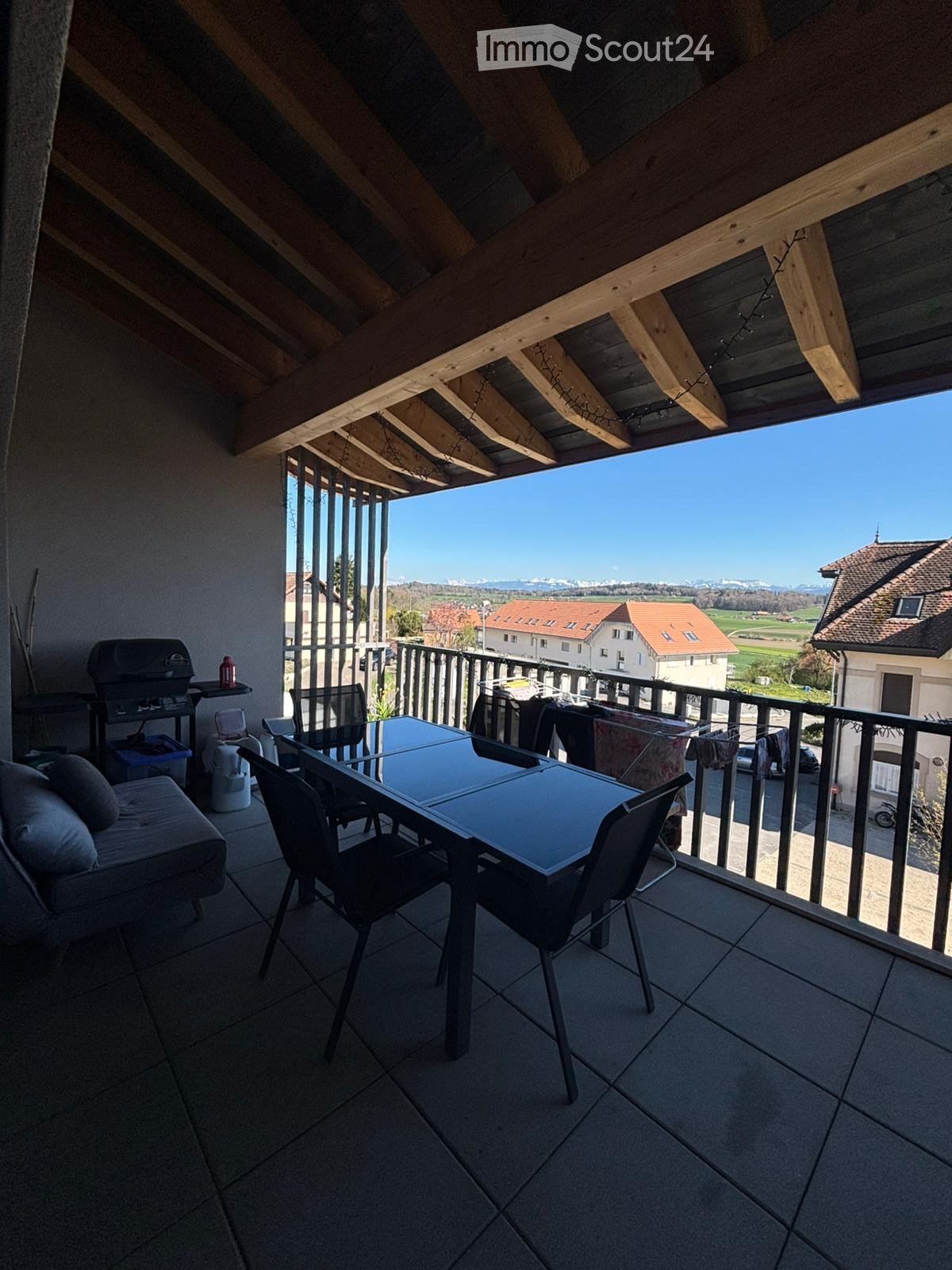 balcony with table and chairs, grill, couch, view of the mountains