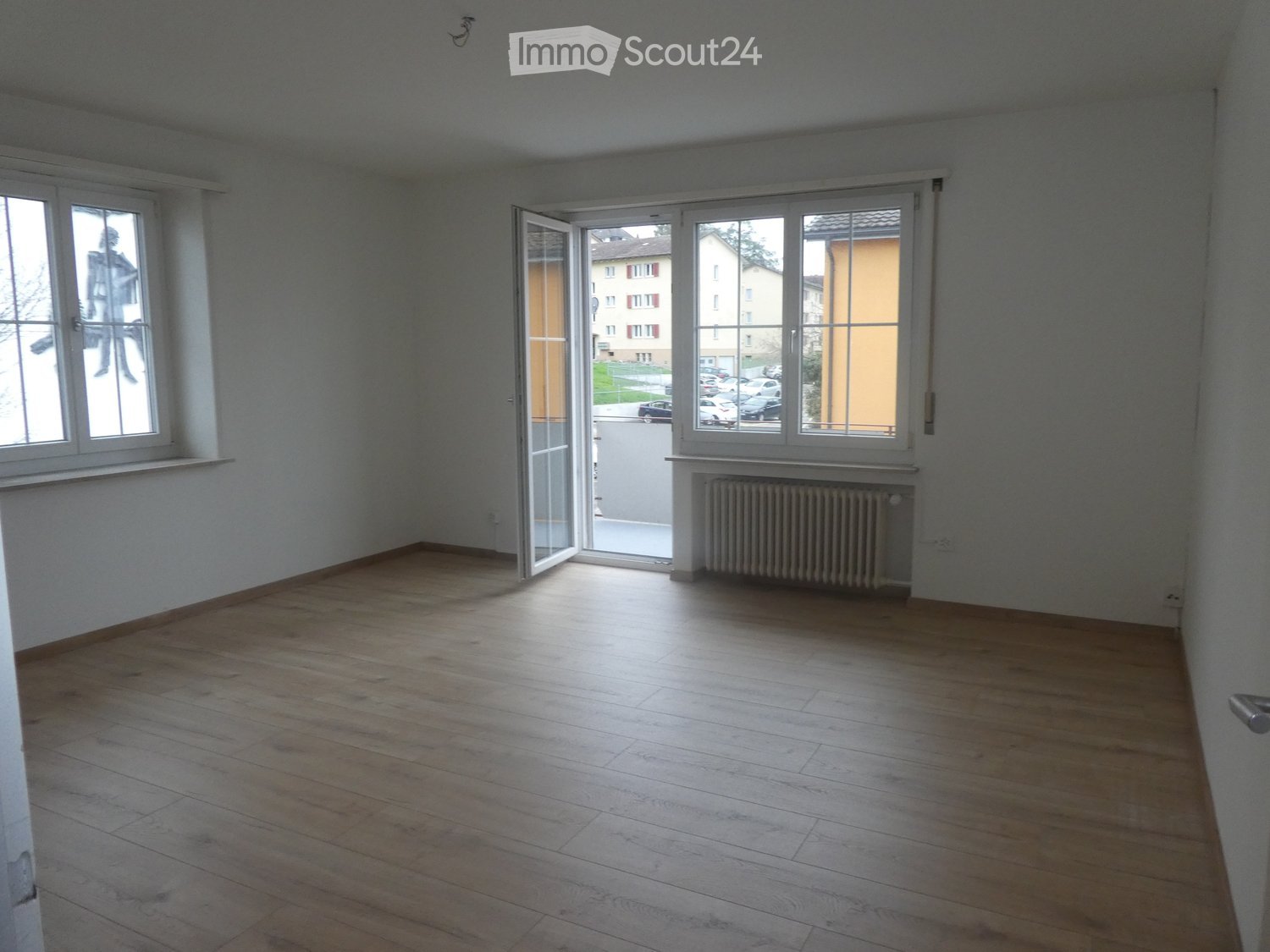 open sliding door, glass window, wooden floor, white walls, radiator