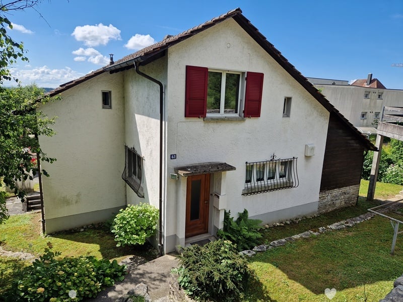 white facade house, red shutters, wooden door, small garden, fence, plants