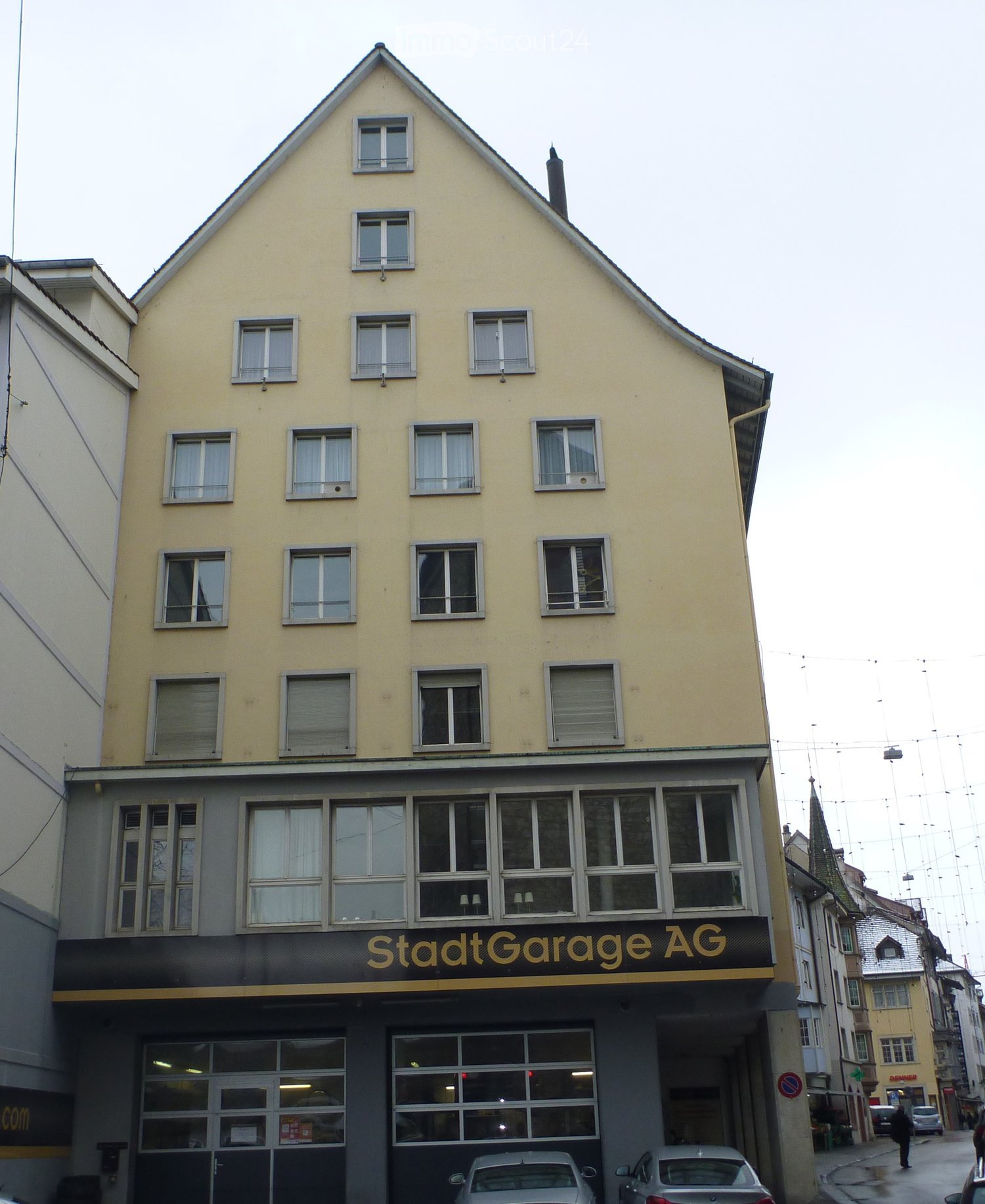Building with multiple stories, labeled 'StadtGarage AG' at the bottom, many windows, cars parked in front