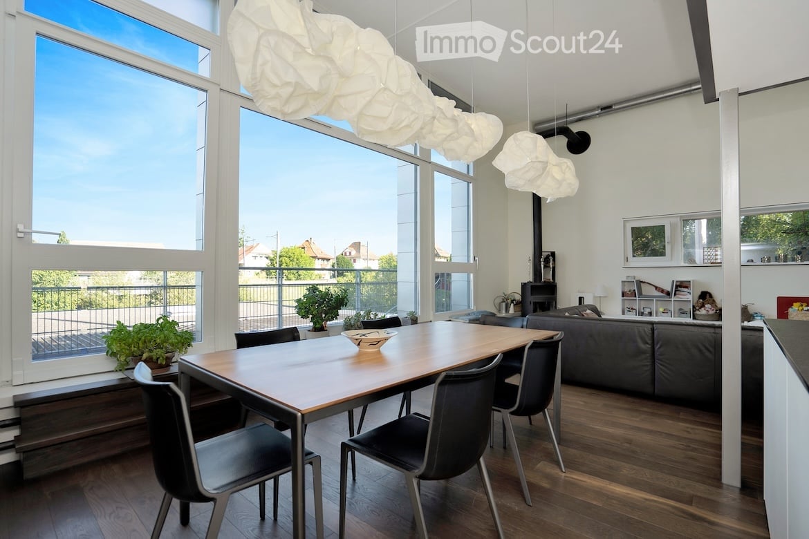 wooden table, black chairs, wooden floors, white walls, large windows, balcony, potted plants, black couch, fireplace, lamps