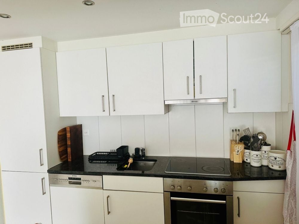 modern kitchen with white cabinets, black countertop, electric stove, oven, dishwasher, white fridge
