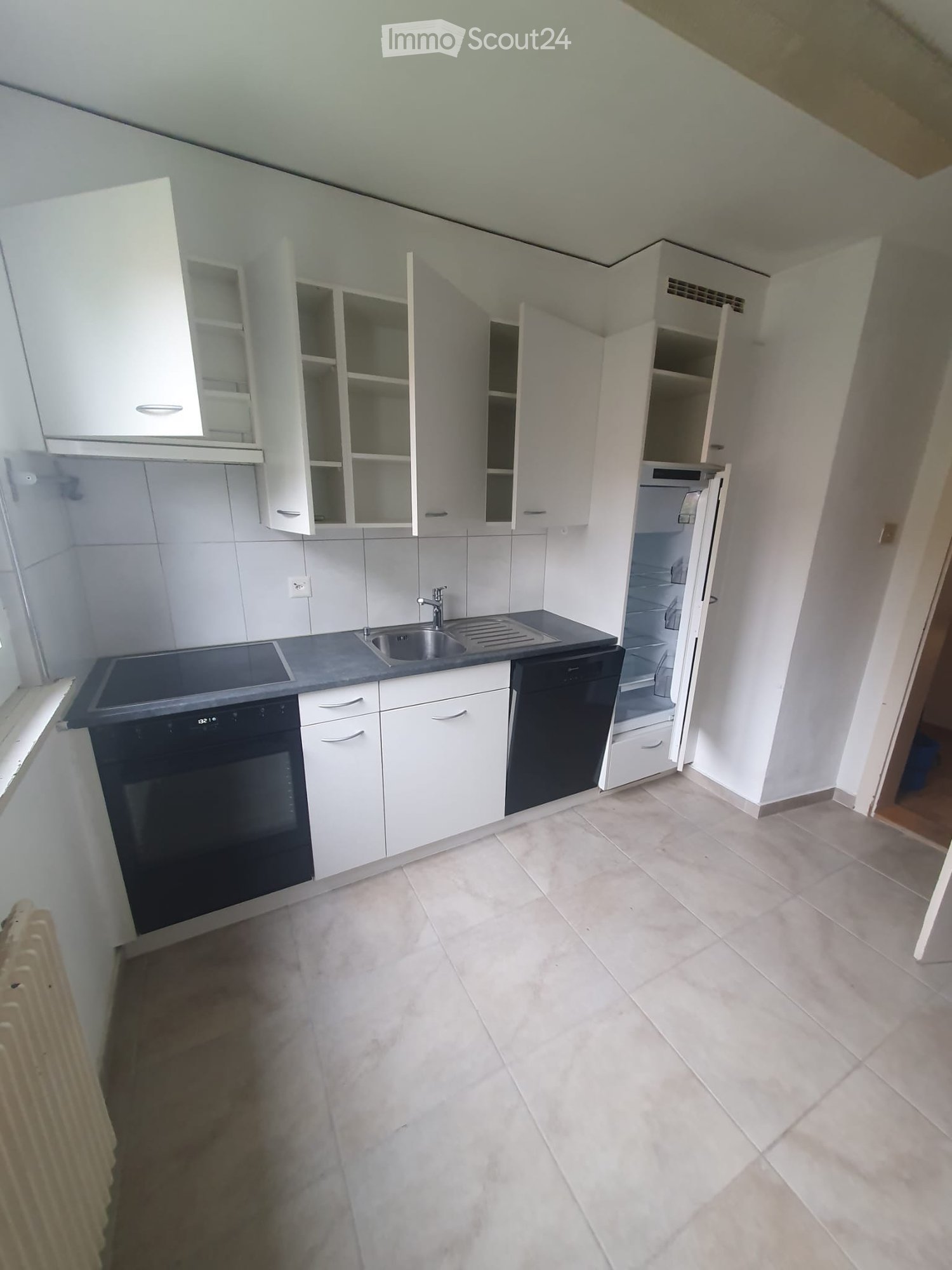 white kitchen with tile floor, kitchen appliances, white cabinets, stainless steel sink, open refrigerator