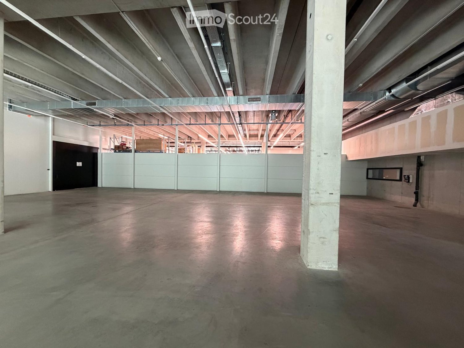 Empty room with concrete floor, white walls, metal beams, and a central pillar.