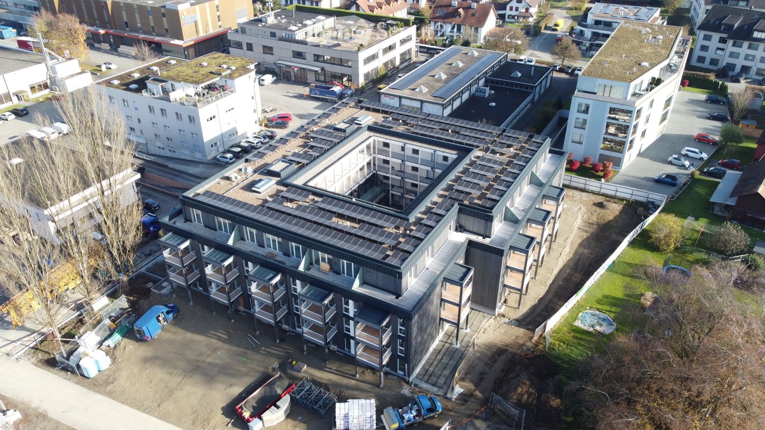 multi-story residential building with solar panels on the roof, construction site in progress
