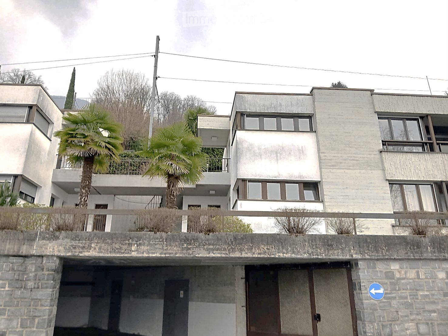 Modern architectural style, concrete and glass, multiple floors, balconies, palm trees, brick wall, entrance