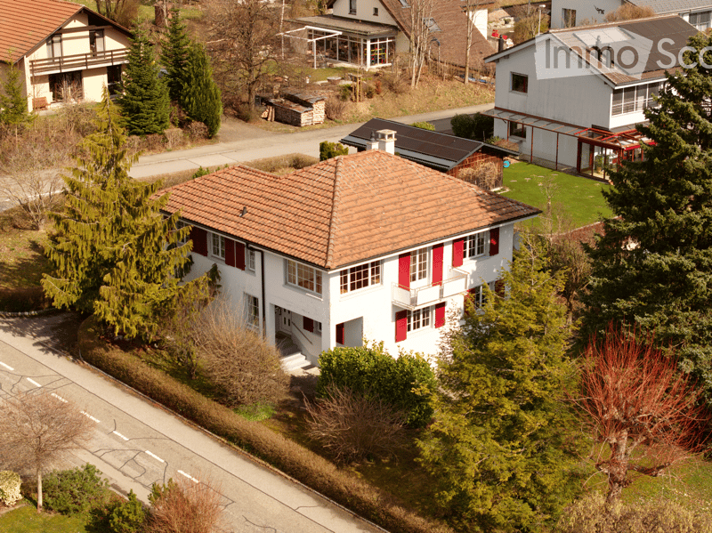 2 story house, brown roof, red shutters, solar panels, surrounded by trees