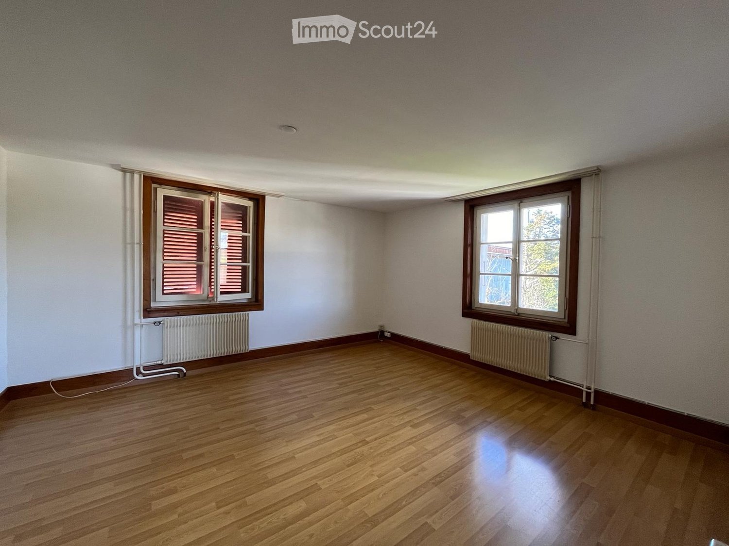 empty room, wooden floor, white walls, two windows, radiators