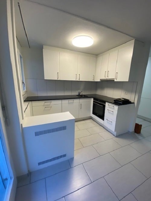 modern kitchen, white cabinets, black countertops, white tiles, built-in oven, dishwasher, washing machine