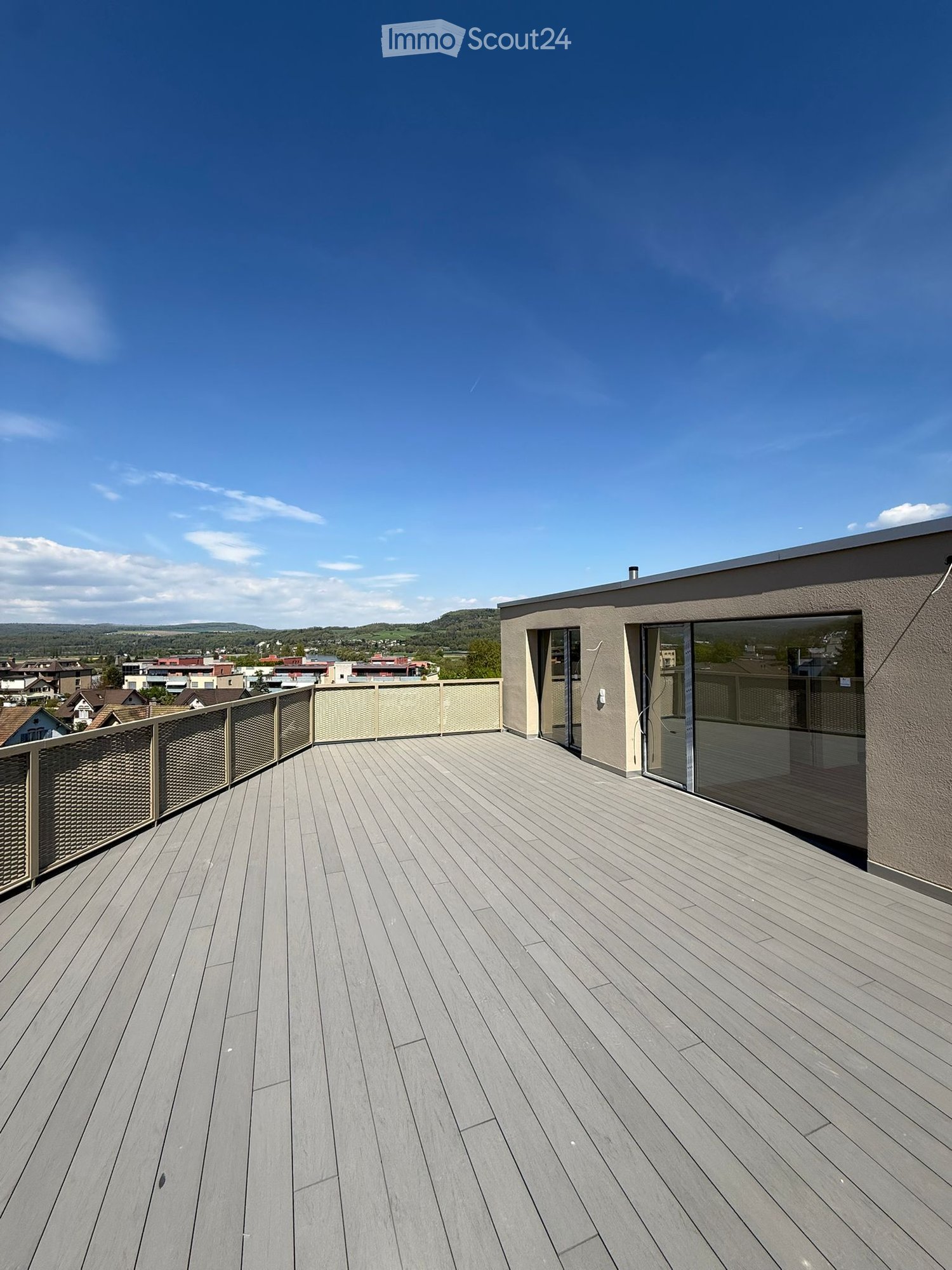 Roof terrace with wooden floor, metal railing, glass doors, view of the city