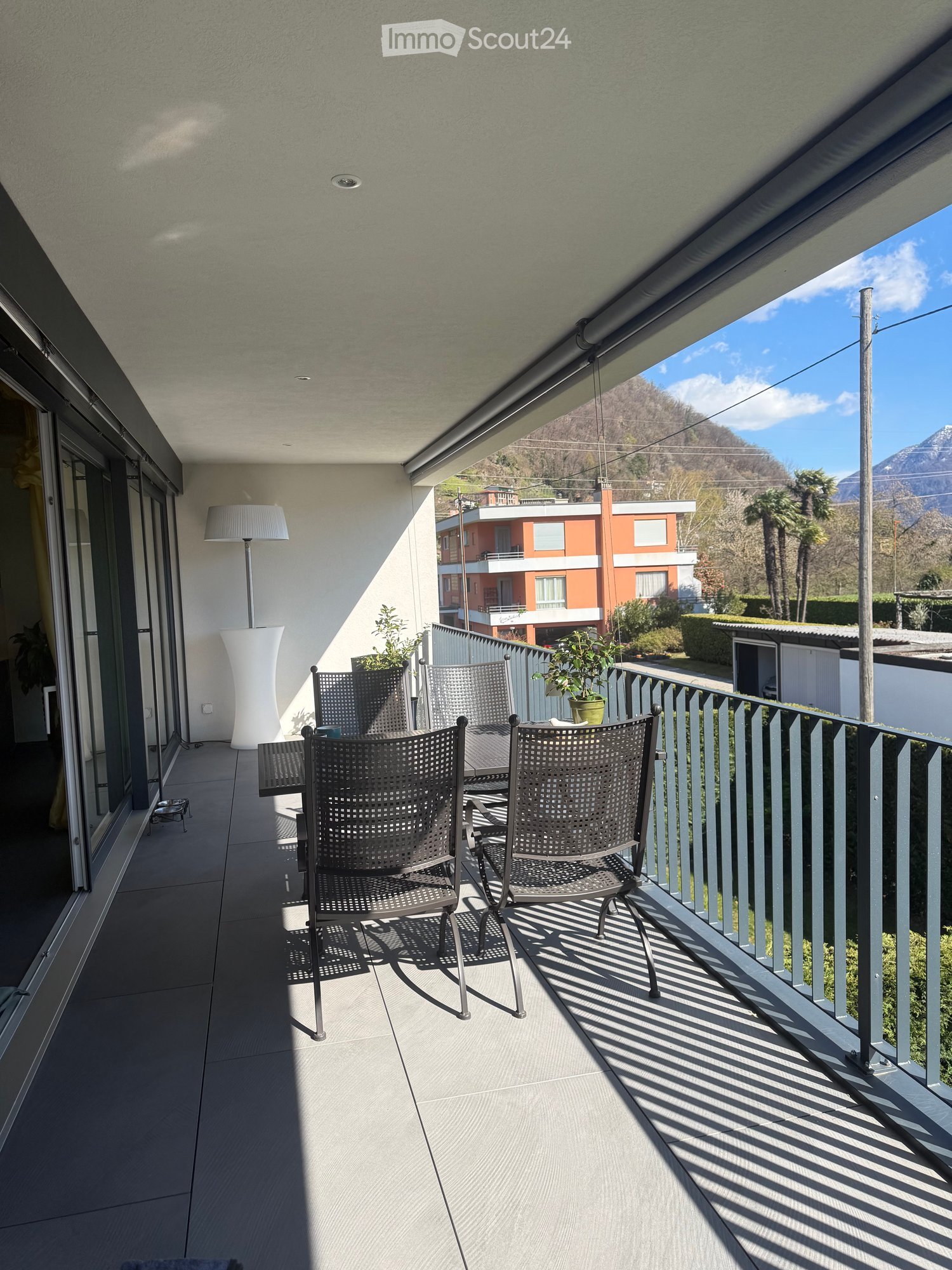 Balcony with table and chairs, floor lamp, plants, railing, view of mountains