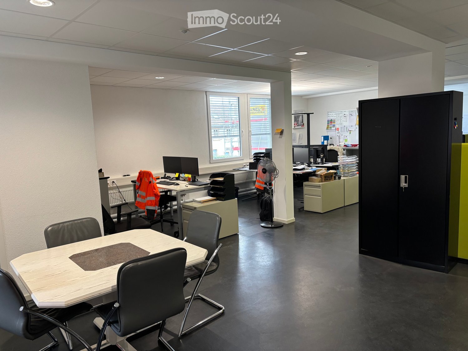 modern office space with desks, chairs, computer monitors, storage cabinets, and a table