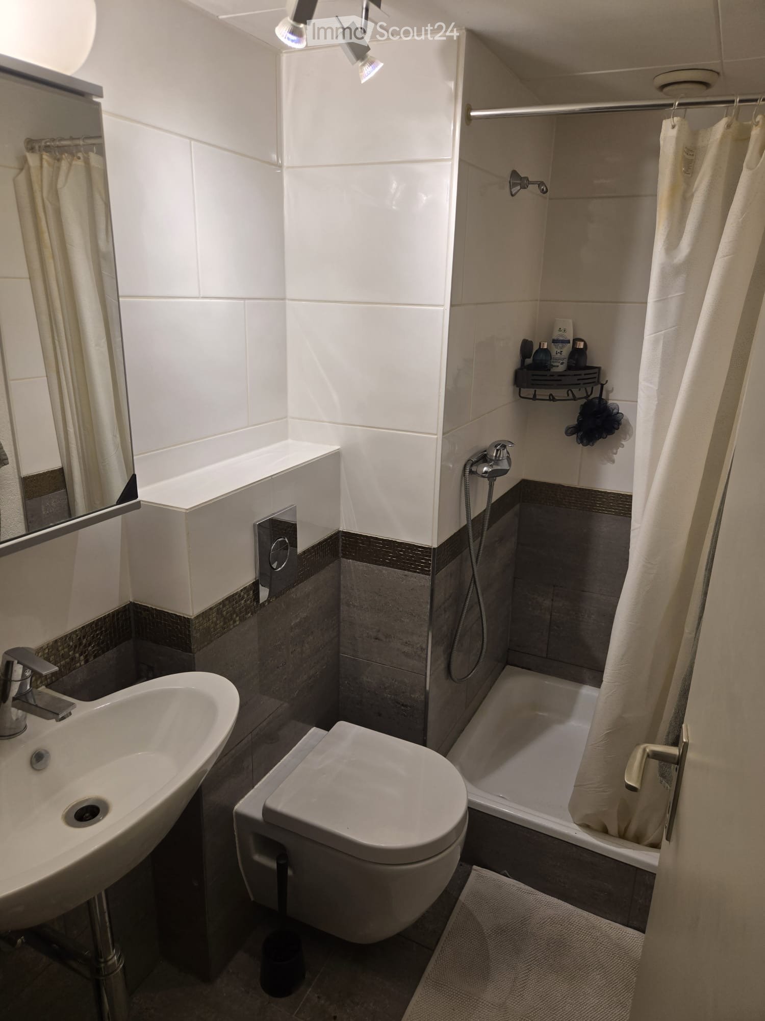modern bathroom with white tiles, white sink, white toilet, shower with shower curtain, mirror, and shower head