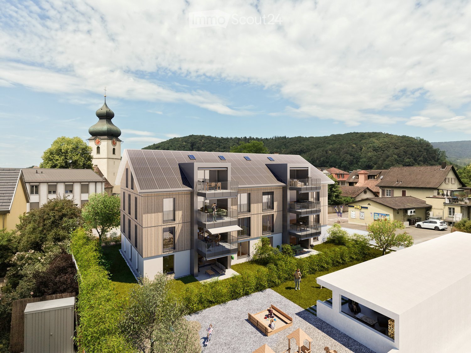 A modern multi-story residential building with balconies and solar panels on the roof, surrounded by greenery and a small courtyard with seating areas.