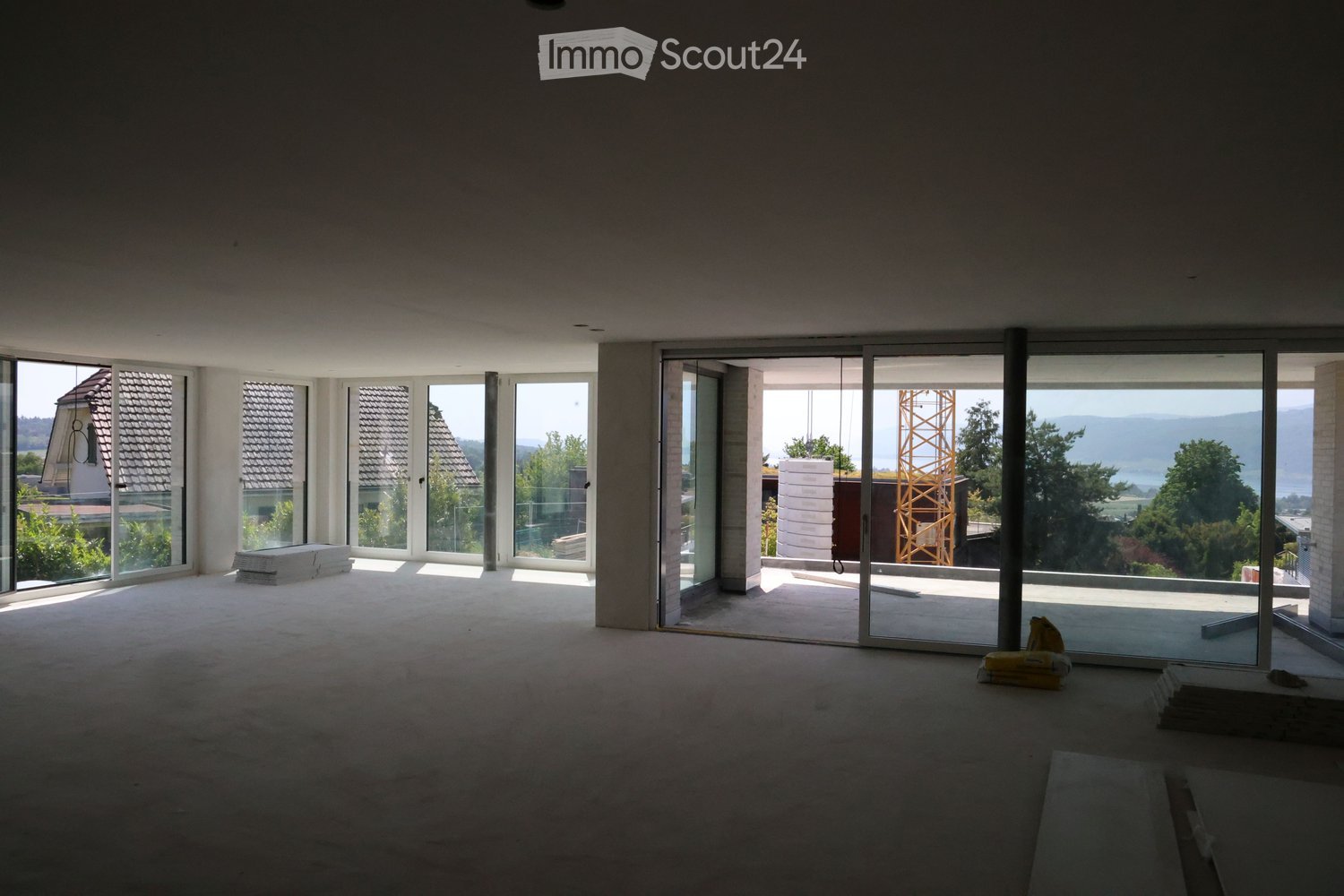 Empty room with large windows and sliding glass doors leading to a balcony, natural light flooding the space.