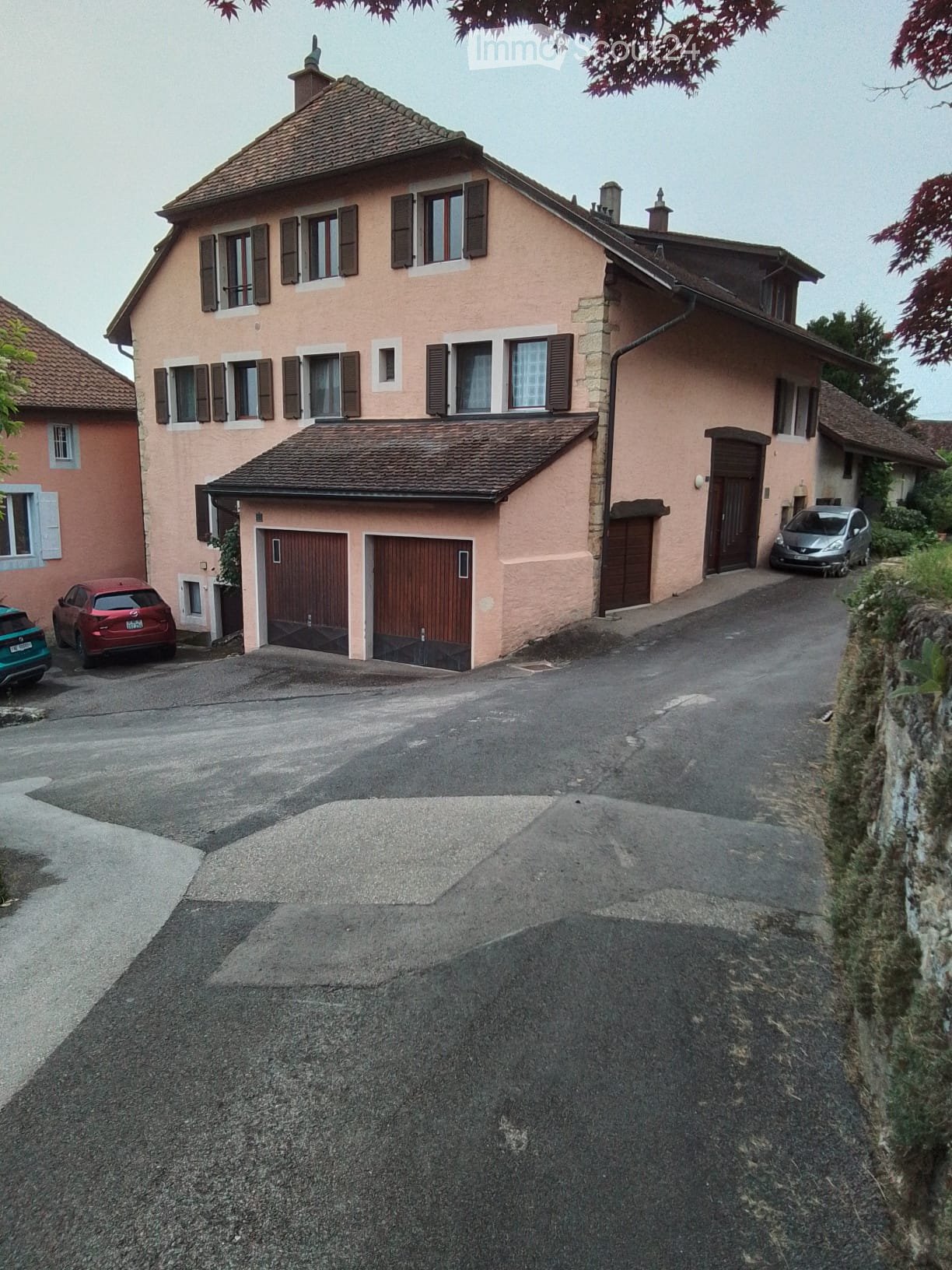 2 story house, pink exterior, brown roof, 2 garages, 3 cars parked
