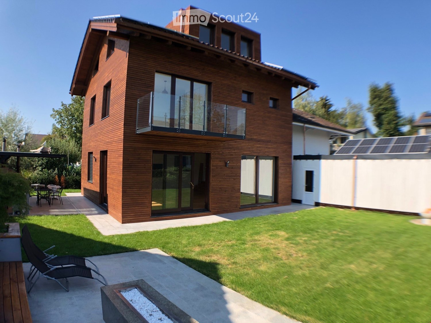 modern house, brown wooden exterior, glass doors, balcony, solar panels, garden, patio