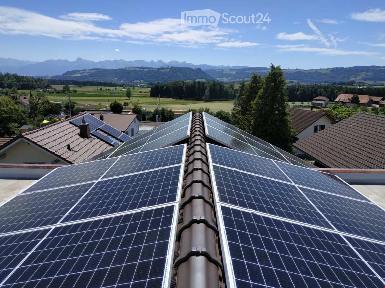 House with solar panels on the roof, brown roof tiles, multiple houses in the background, mountains in the distance