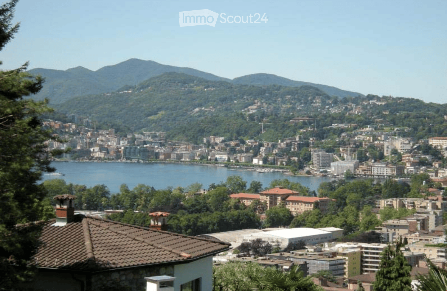House with brown roof, overlooking a city with mountains in the background
