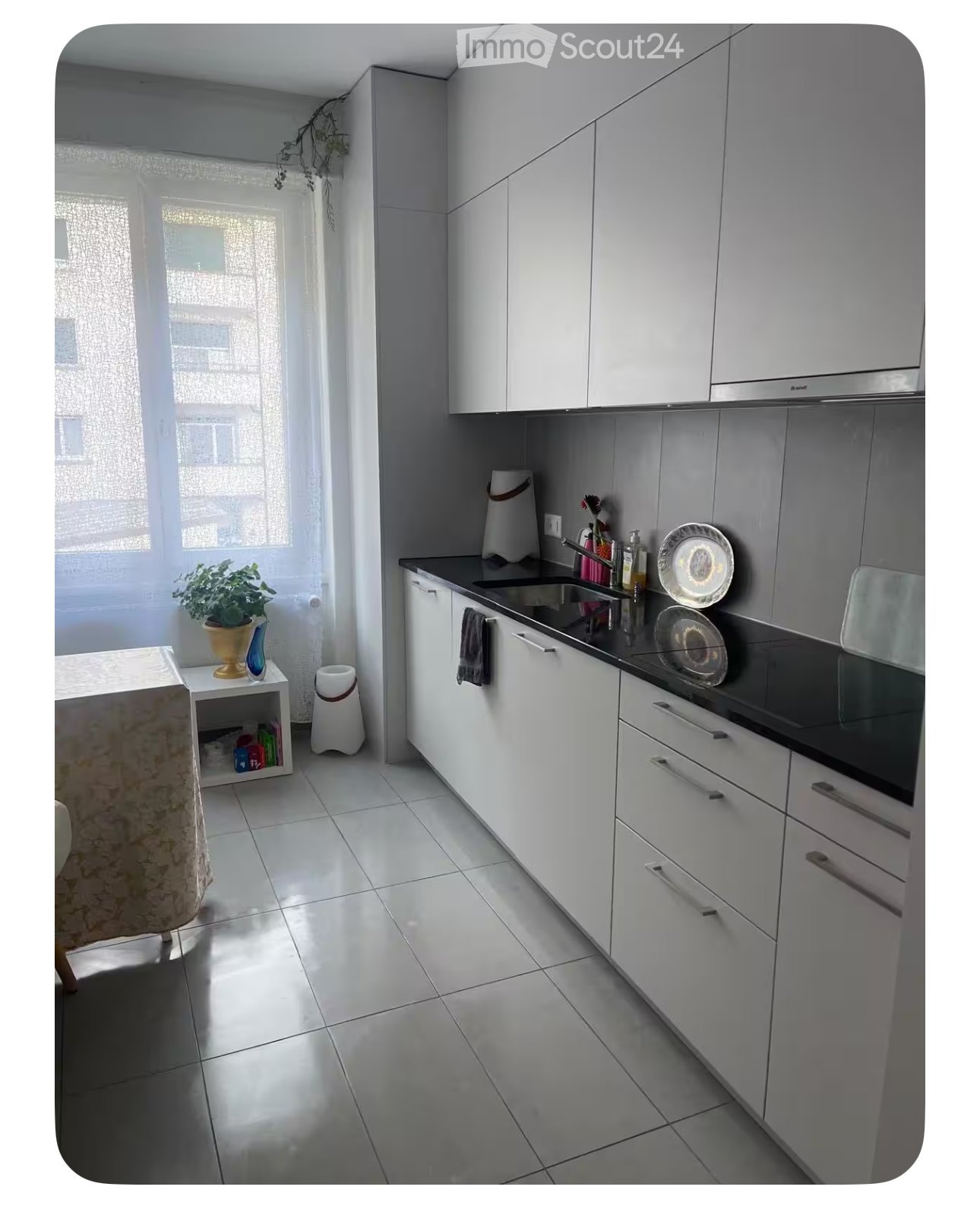 modern kitchen with white cabinets, black countertops, stainless steel sink, dishwasher, window with curtains