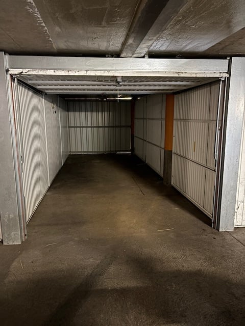 Empty garage with metal walls and ceiling, concrete floor, open door, and a light fixture