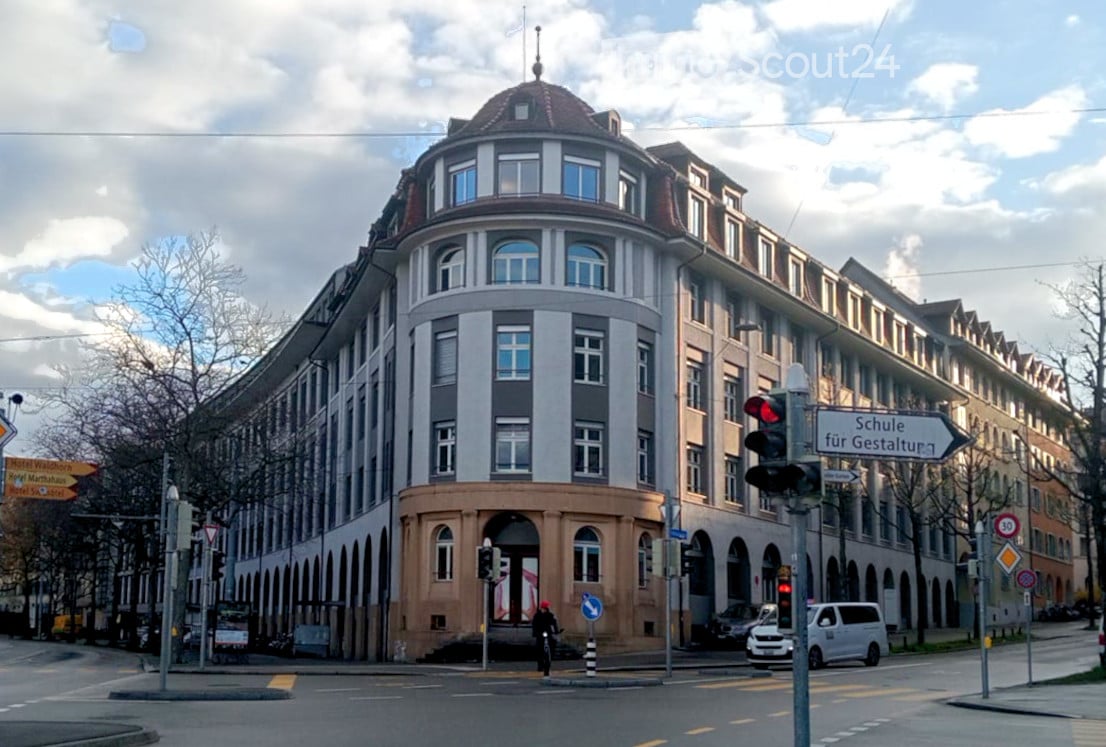 large building with multiple windows, brown roof, arched windows, street signs, traffic lights