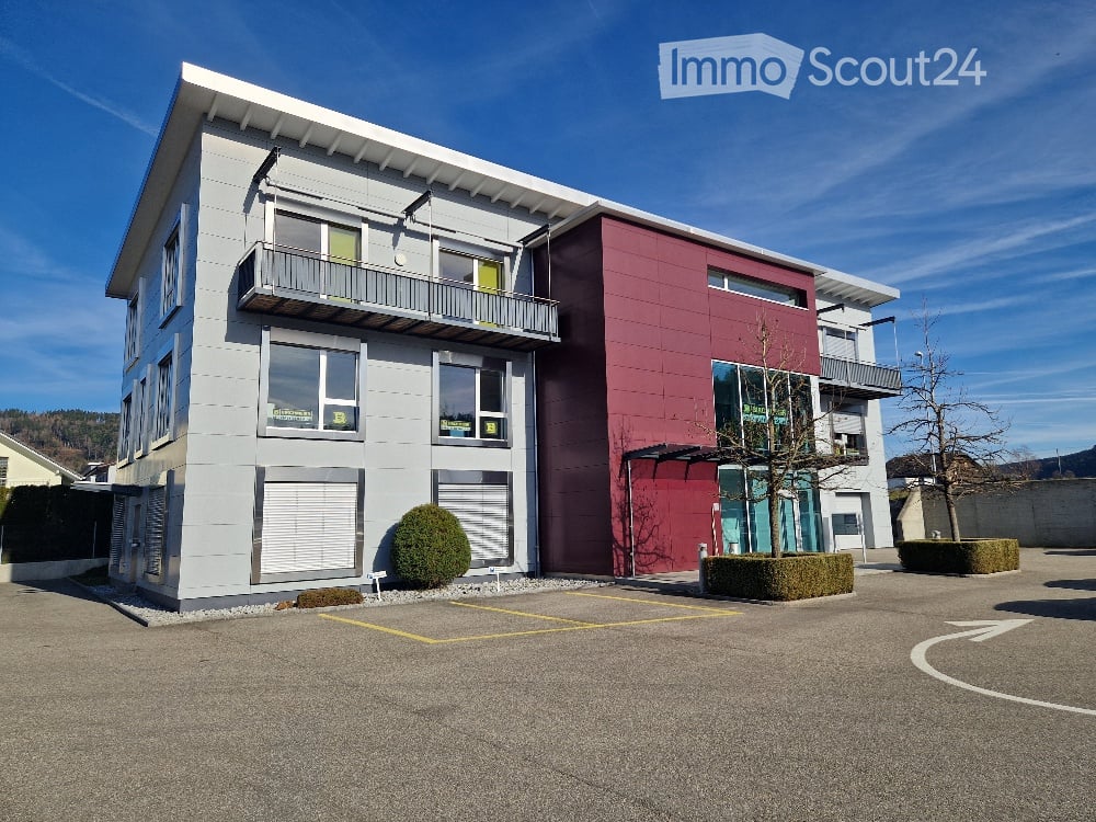 2 story building, gray and red exterior, 2 balconies, parking area
