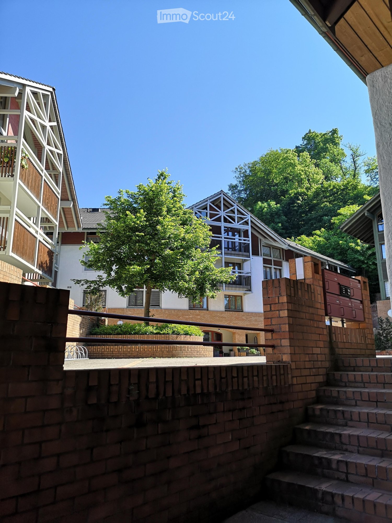 A building with balconies, brick walls, and a tree in front