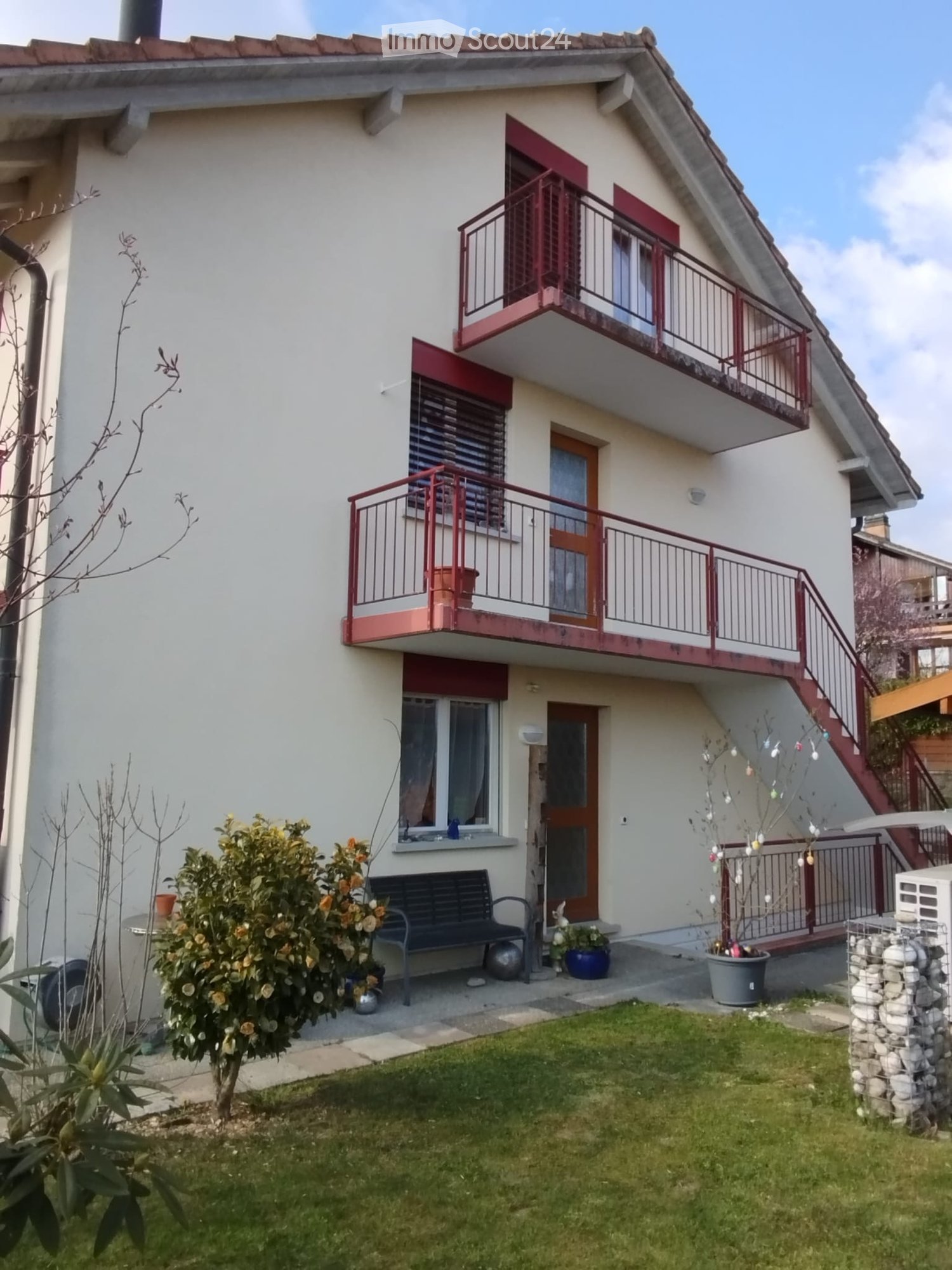 2 story house, white exterior, red balconies, front yard with bench and plants