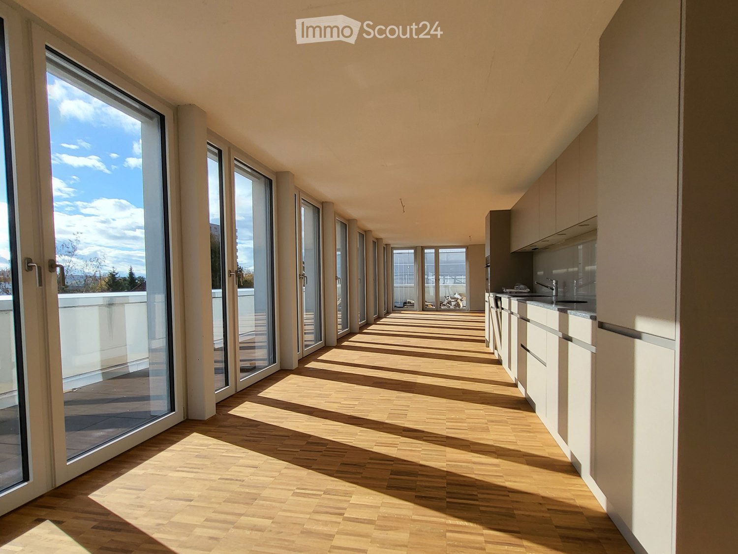 long hallway, wooden floor, large windows, balcony, kitchen