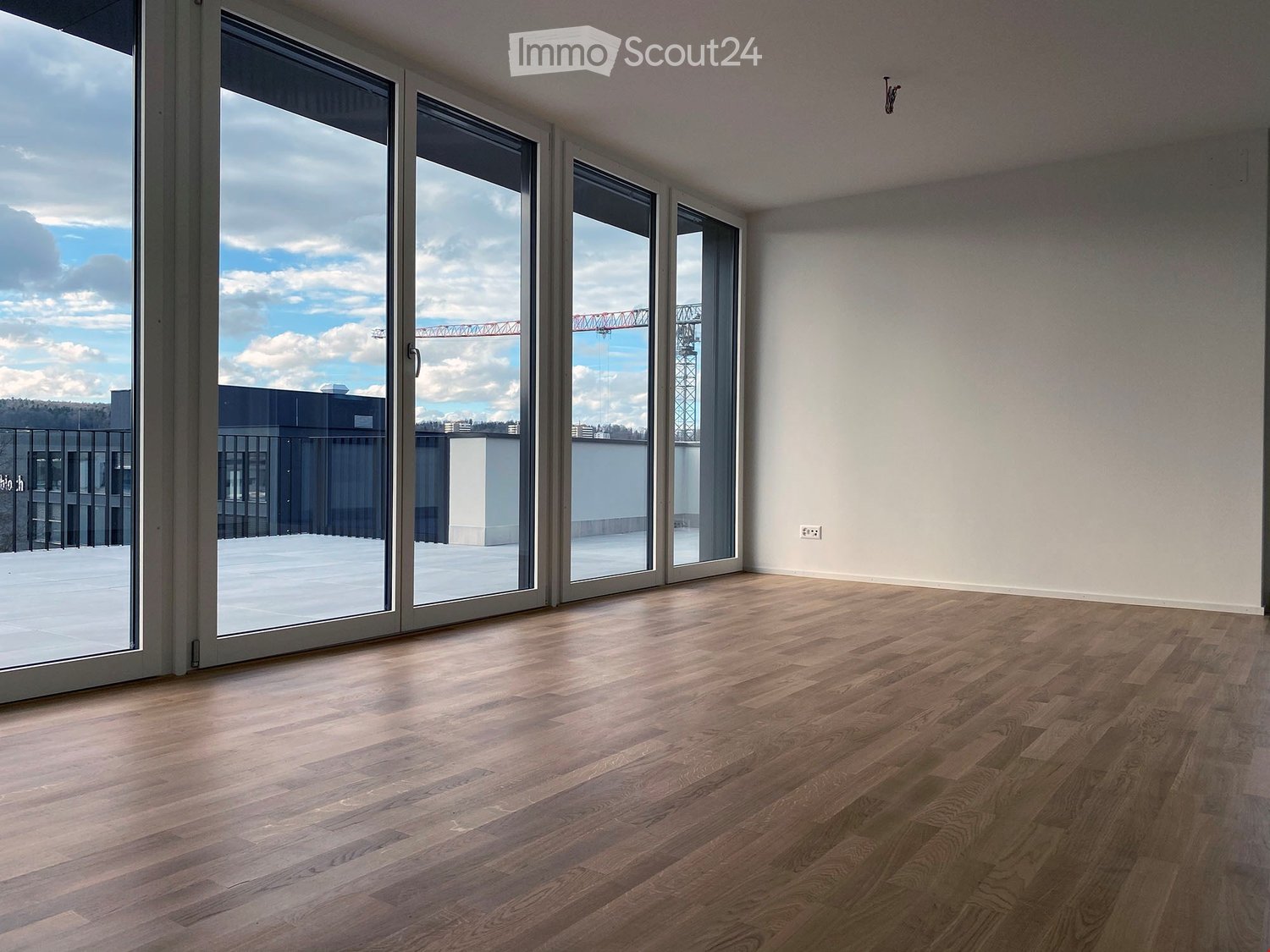 sliding glass doors, hardwood floors, white walls, balcony with black railings, power outlet, cityscape view