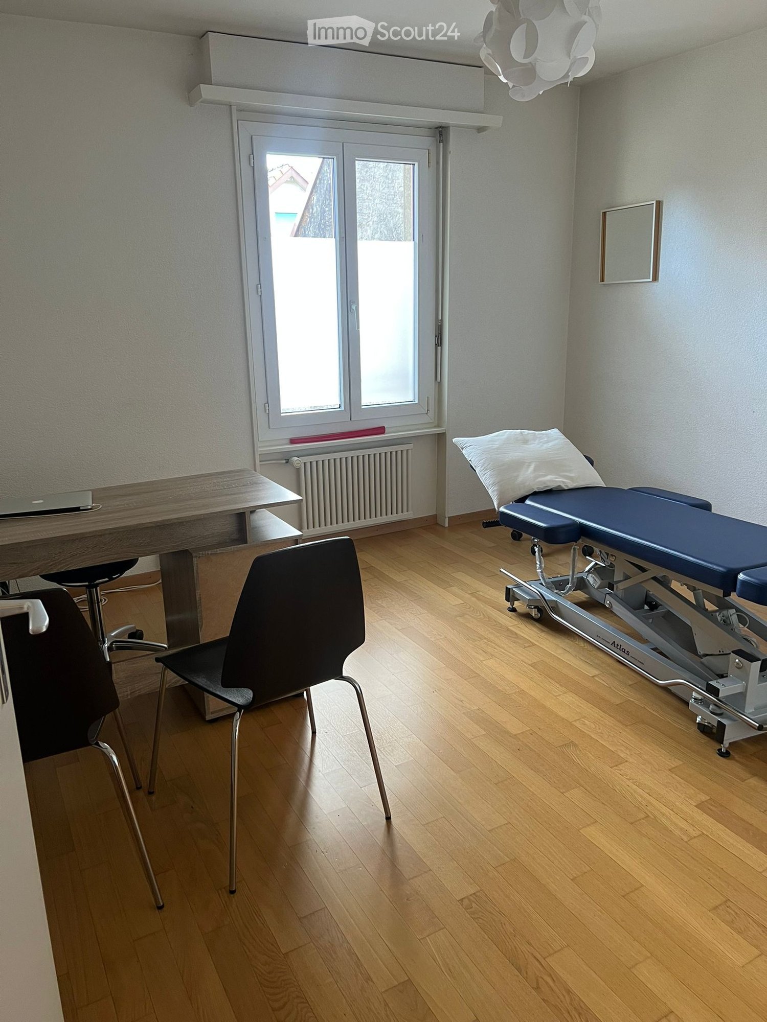 medical room with medical bed, desk, chair, radiator, windows