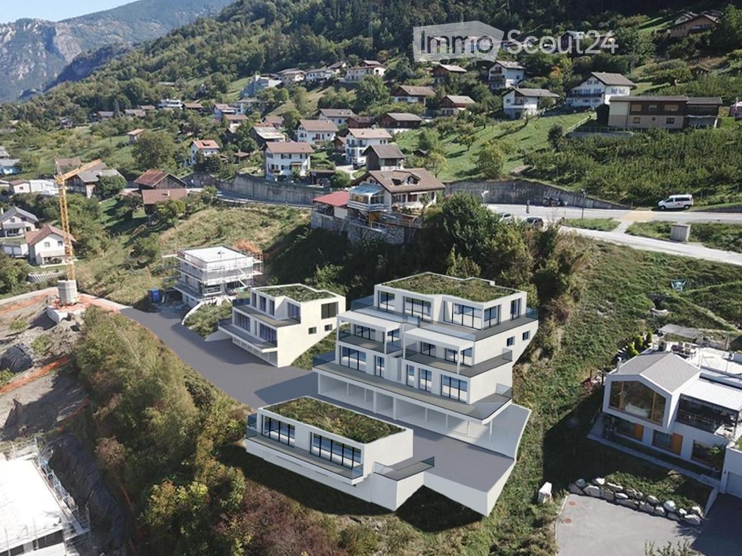 Modern multi-story house, green roofs, large windows, surrounded by other houses, mountainous area