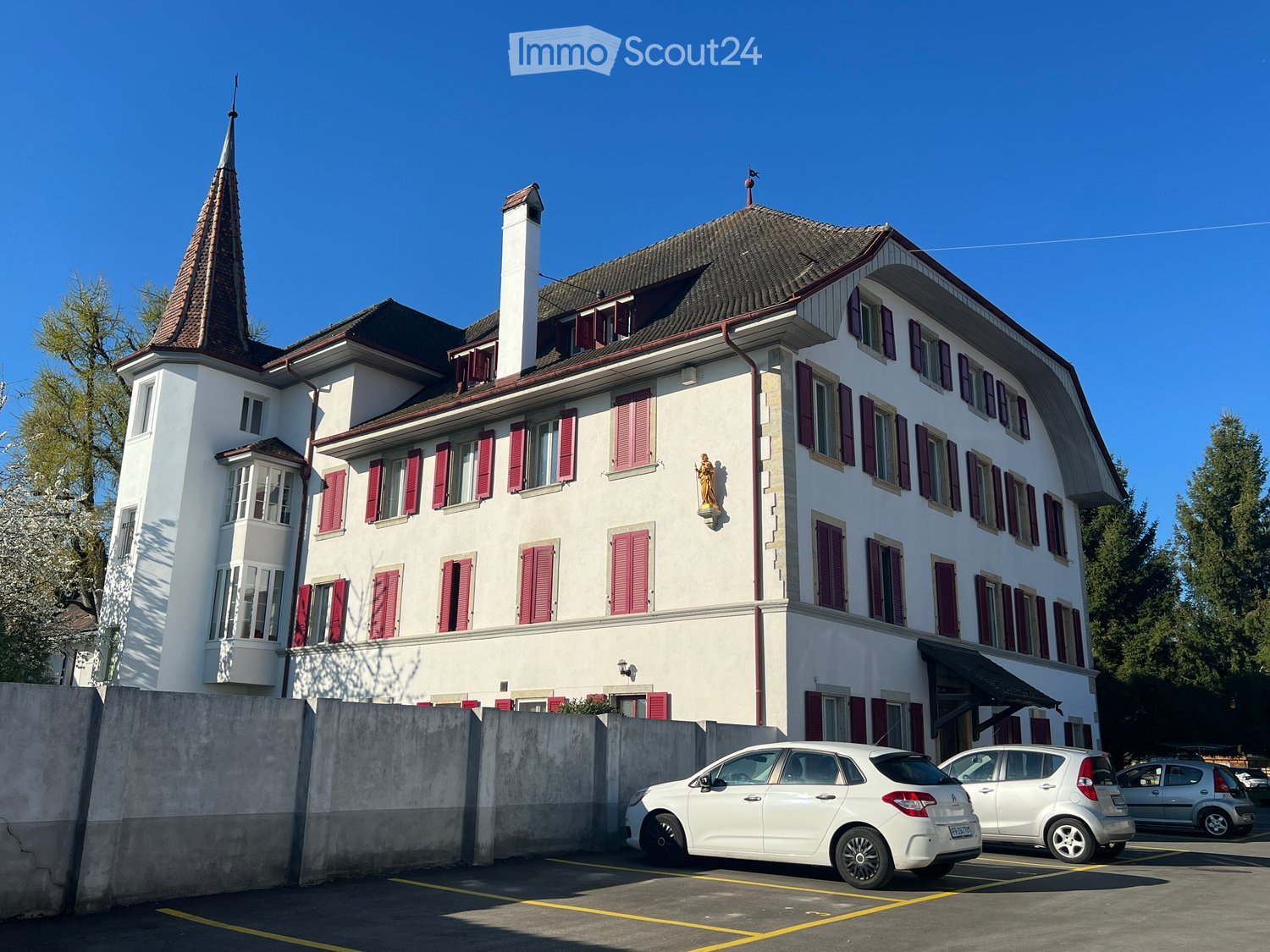 3 story building, white exterior, red shutters, spire, cars parked in front