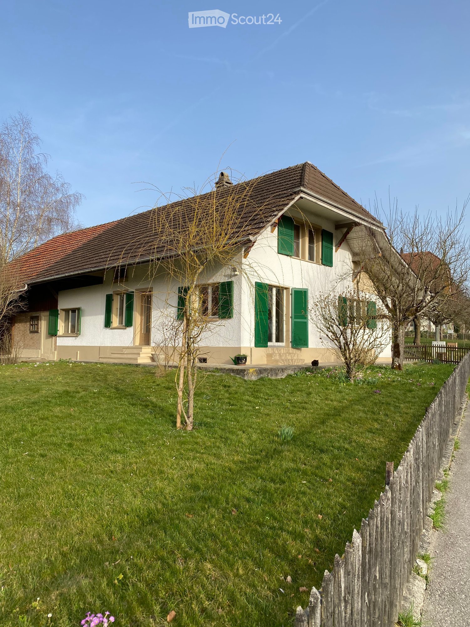 Detached house, white exterior, brown roof, green shutters, well-maintained garden, wooden fence