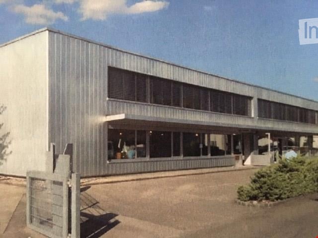 modern industrial building, metal walls, large windows, gated entrance, concrete driveway