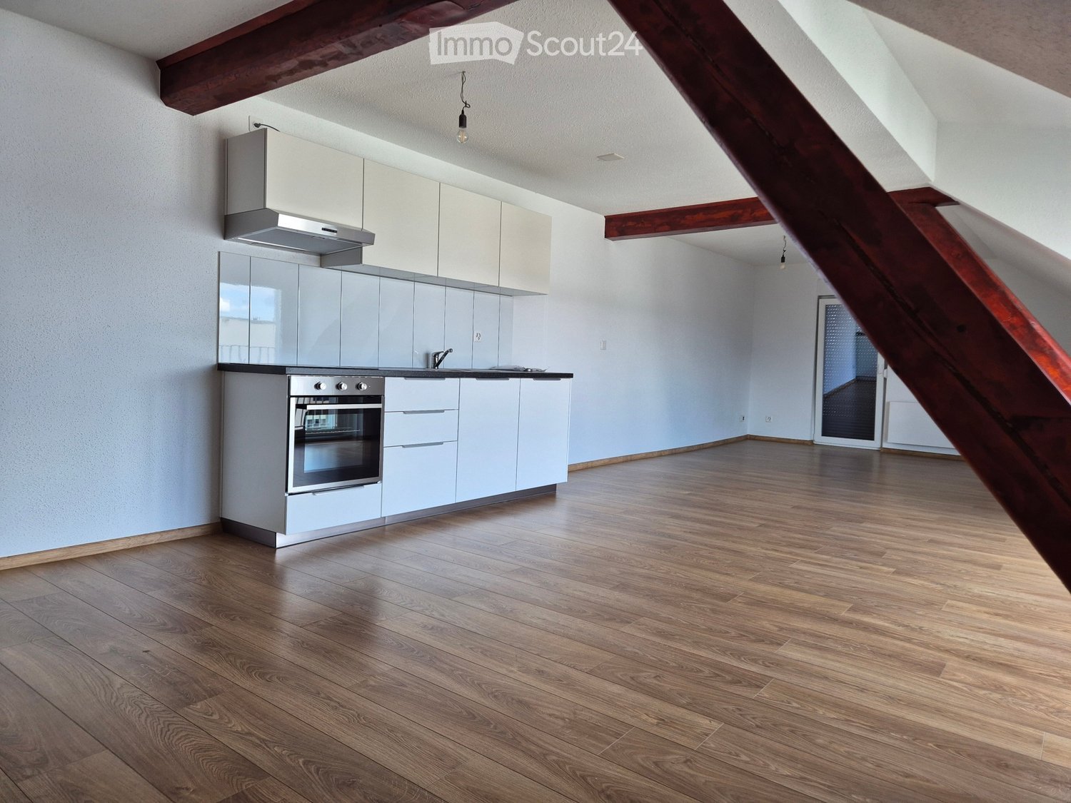 Modern kitchen with white cabinets, stainless steel oven, and wooden flooring.