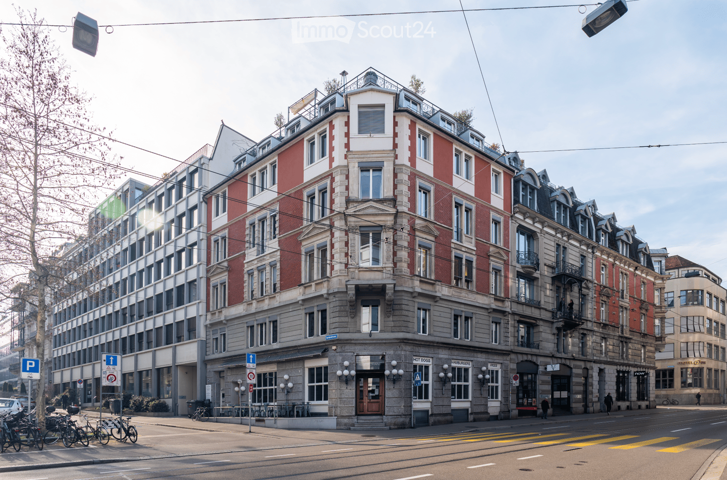 5 story building, red brick, white windows, balconies, awnings, street level shops