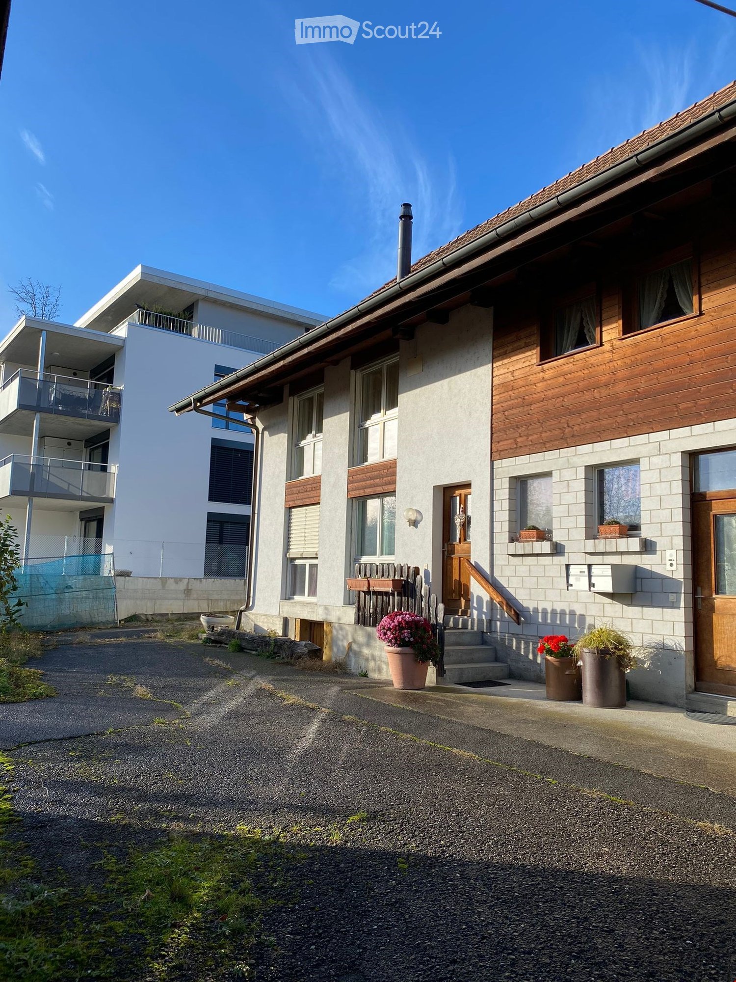 2 story house, white and brown exterior, wooden doors, windows, balcony, potted plants