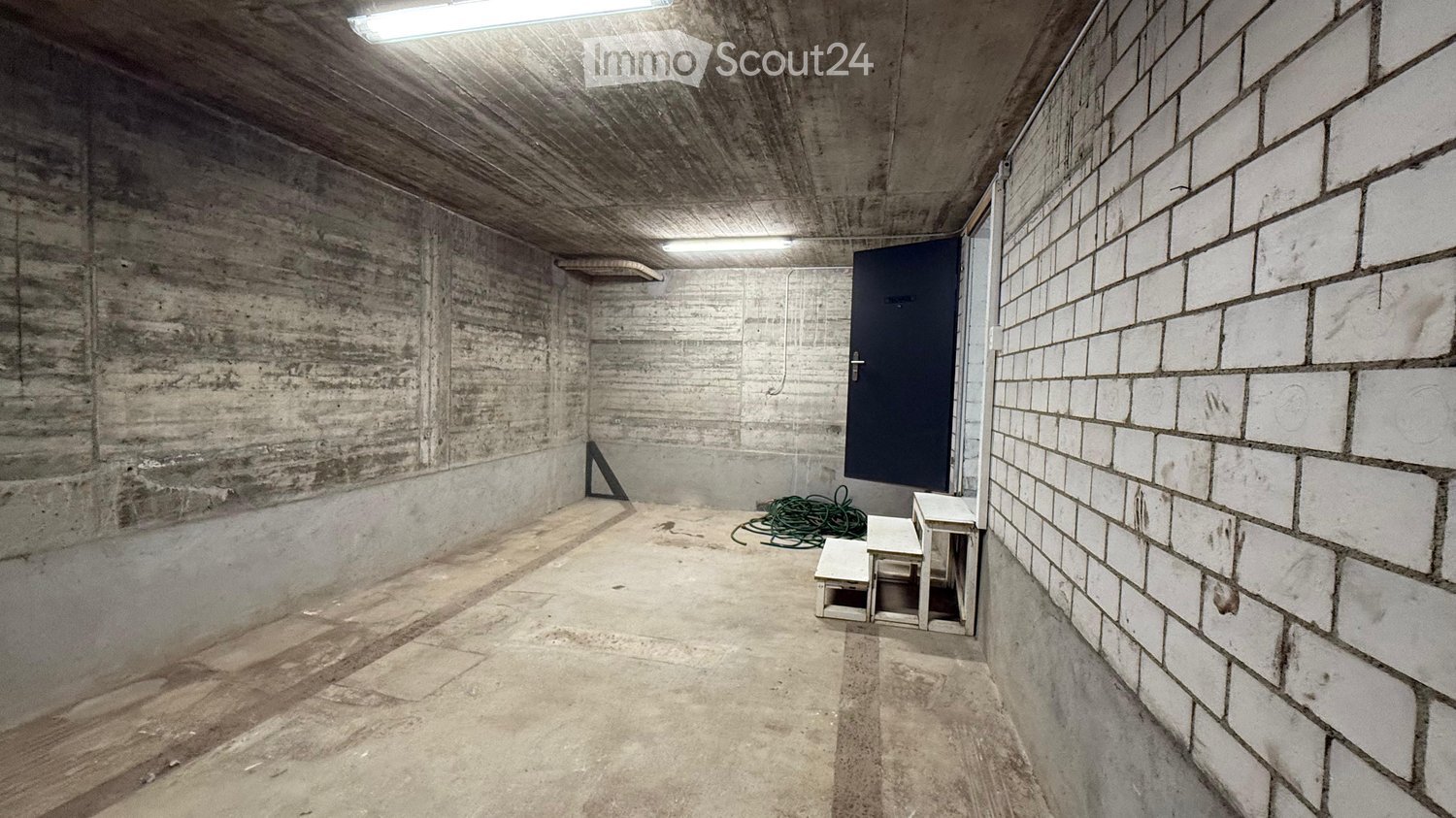 empty room, concrete walls, concrete floor, two small steps, door, two lights